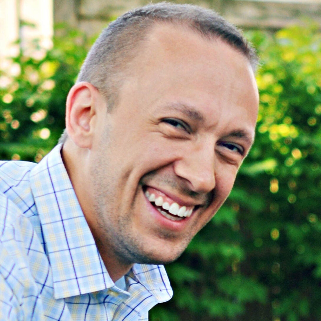 M.S. in Health Informatics alum Jonathan Leigh smiles in front of greenery