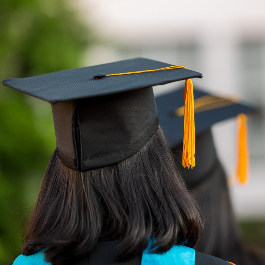 Photo of two graduates looking away with their caps on